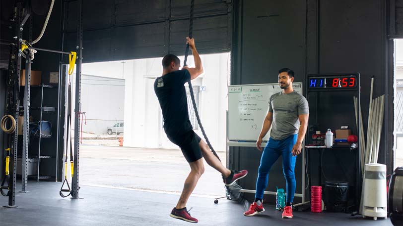 A man climbing rope in a gym