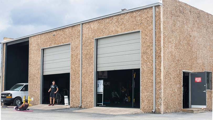 two men working out next to a garage