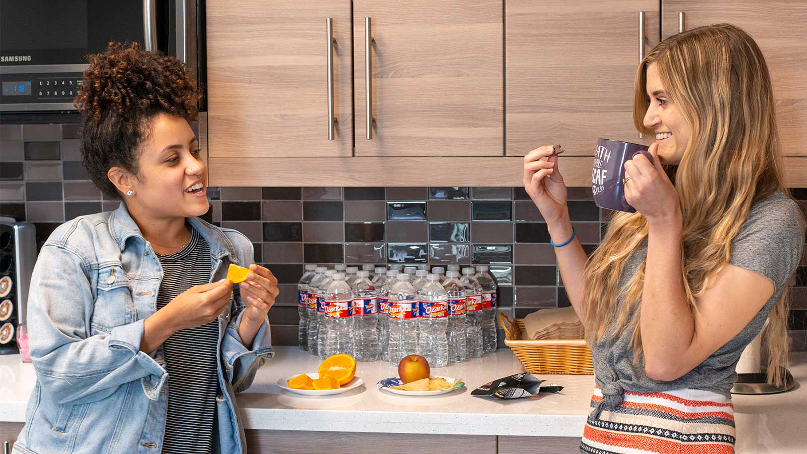 Two women sharing a snack together in a kitchen